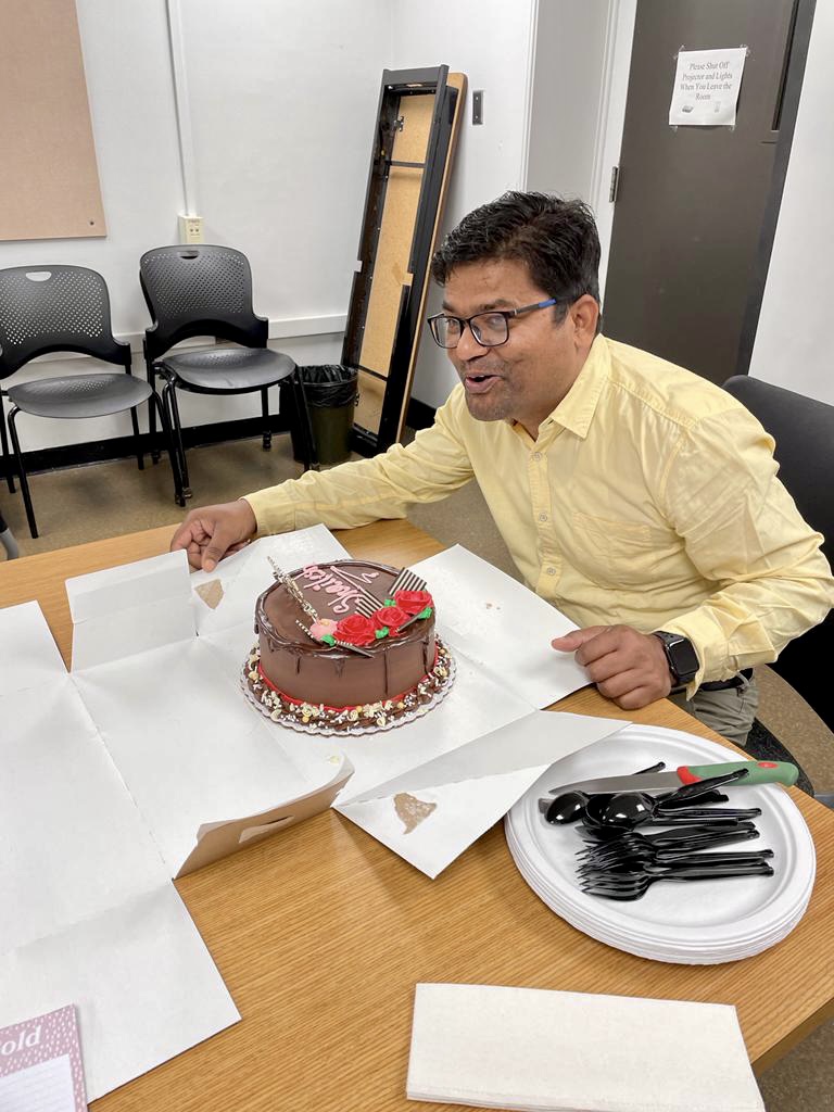 A person smiling in front of a cake