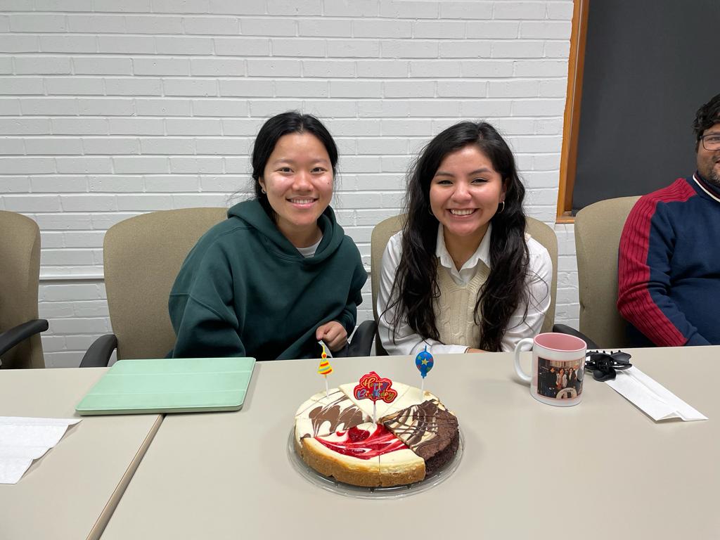 Two people smiling in front of a birthday cake